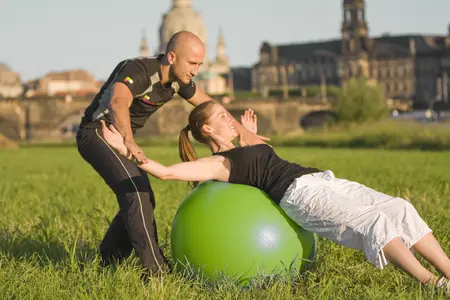 Von einem Trainer angeleitete Übung auf einem Gymnastikball zur Stärkung der Rumpfmuskulatur